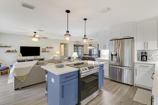 kitchen with blue cabinetry, white cabinetry, stainless steel appliances, a kitchen island, and decorative light fixtures