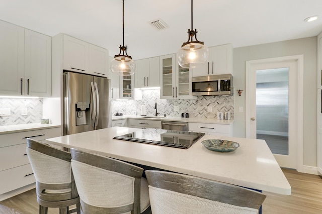 kitchen with white cabinetry, appliances with stainless steel finishes, a center island, and light hardwood / wood-style flooring