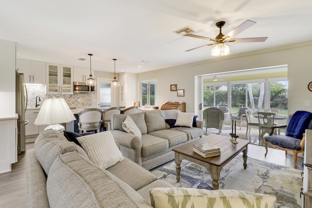 living room with ceiling fan, sink, and light hardwood / wood-style floors