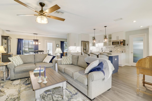 living room with sink, ceiling fan, and light wood-type flooring