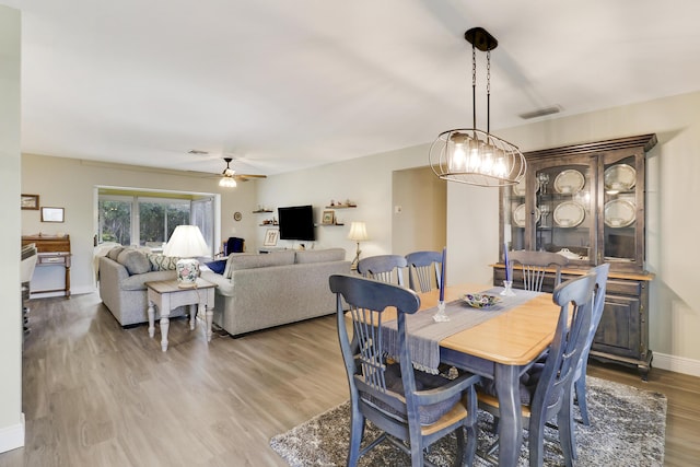 dining space featuring hardwood / wood-style flooring and ceiling fan with notable chandelier