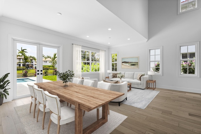 dining space with ornamental molding, french doors, and light wood-type flooring