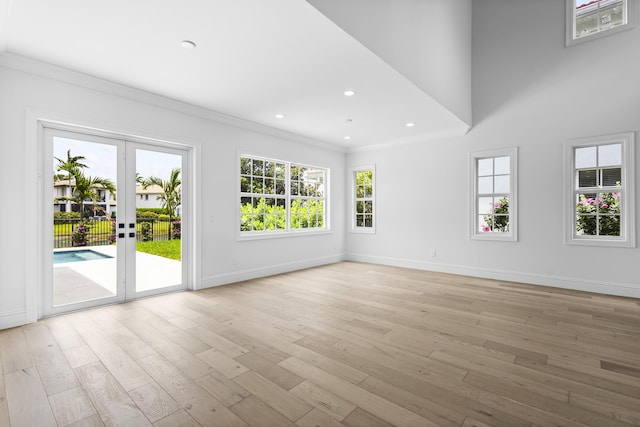 empty room featuring french doors, ornamental molding, and light hardwood / wood-style floors