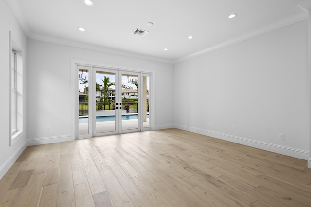 empty room featuring crown molding, french doors, and light wood-type flooring