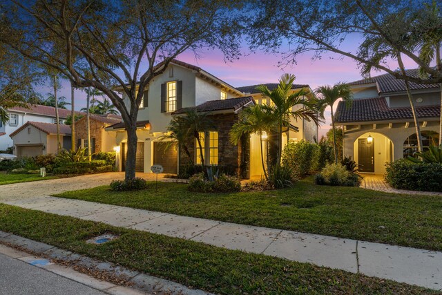 mediterranean / spanish house featuring a garage and a front lawn