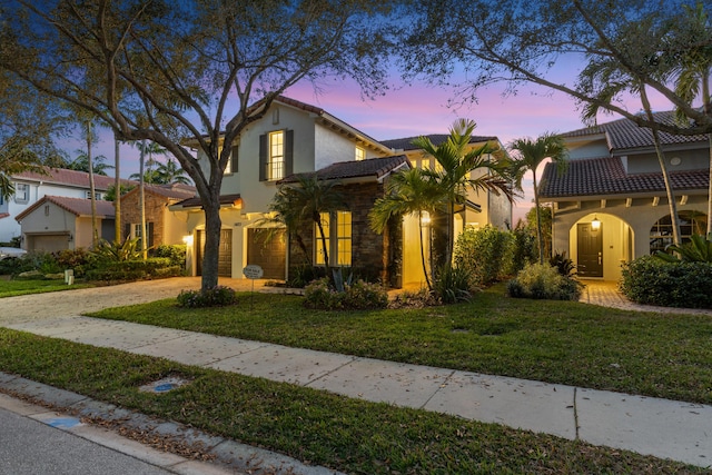 mediterranean / spanish-style home with a garage and a lawn