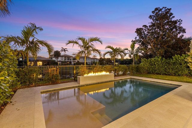 pool at dusk with a patio area