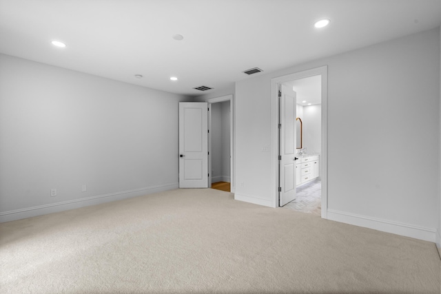 unfurnished bedroom with connected bathroom and light carpet