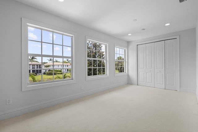 unfurnished bedroom with multiple windows, a closet, and carpet flooring