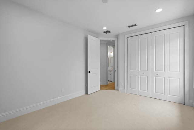 unfurnished bedroom with light colored carpet and a closet