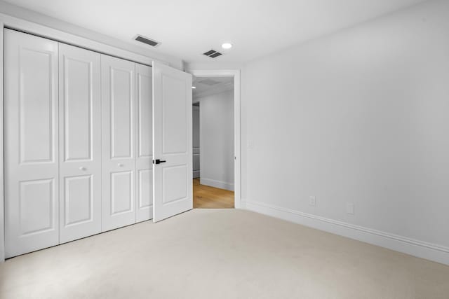 unfurnished bedroom featuring light carpet and a closet