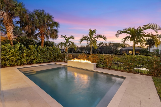 pool at dusk featuring a patio