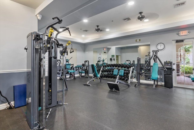 exercise room featuring a raised ceiling and ceiling fan