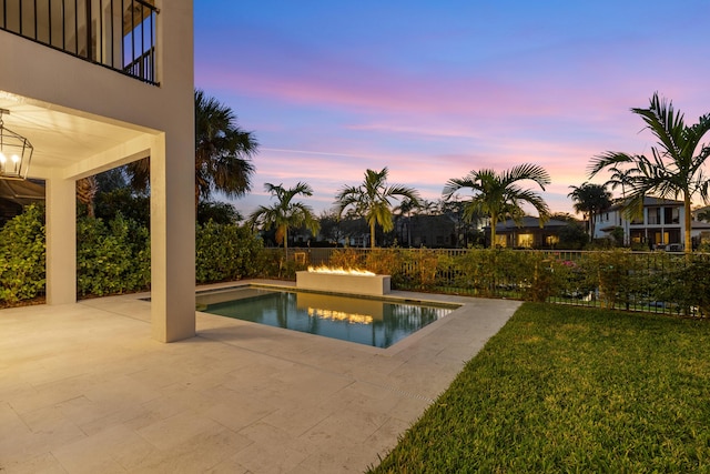 pool at dusk featuring a yard and a patio area