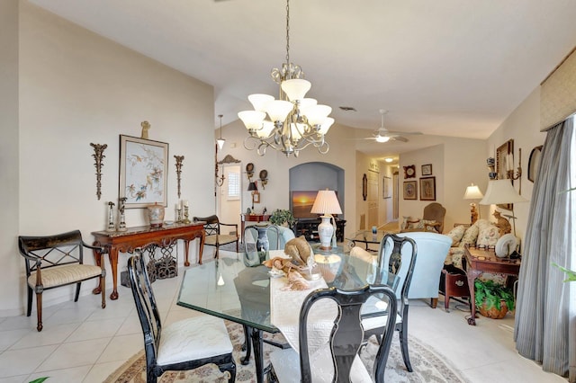 dining room featuring light tile patterned floors, arched walkways, ceiling fan with notable chandelier, visible vents, and vaulted ceiling