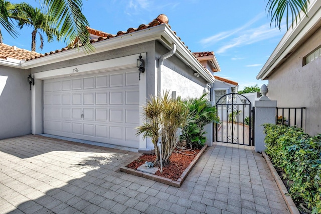 11576 Augustus Dr, Boynton Beach, FL 33437 - view of property exterior featuring stucco siding, a garage, a gate, and a tile roof