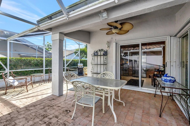 view of patio featuring glass enclosure and a ceiling fan