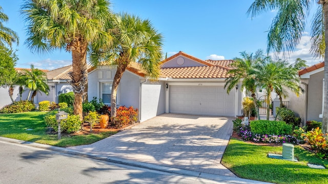 mediterranean / spanish house featuring a garage, decorative driveway, a tile roof, and stucco siding