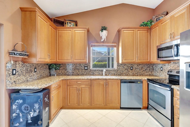 kitchen featuring light tile patterned floors, decorative backsplash, appliances with stainless steel finishes, light stone counters, and a sink