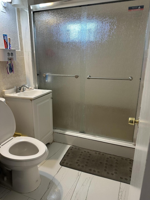 bathroom with toilet, an enclosed shower, sink, and tile walls