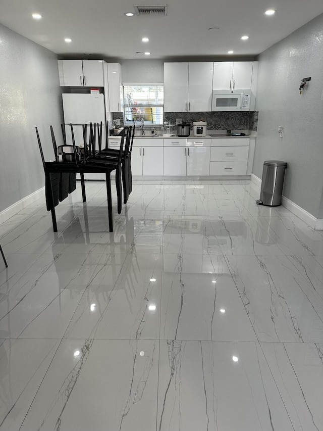 kitchen featuring tasteful backsplash, white cabinetry, sink, and white appliances