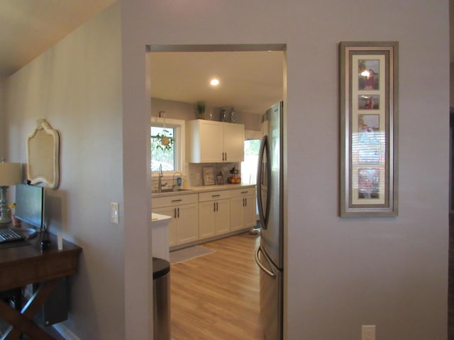 kitchen featuring tasteful backsplash, white cabinetry, stainless steel fridge, and light hardwood / wood-style floors