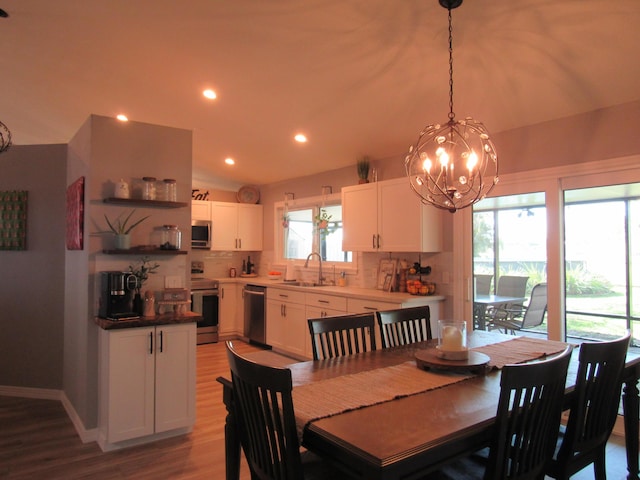 dining space featuring sink, an inviting chandelier, and light wood-type flooring