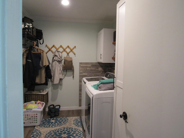 laundry area featuring cabinets, ornamental molding, wood-type flooring, and washer and clothes dryer