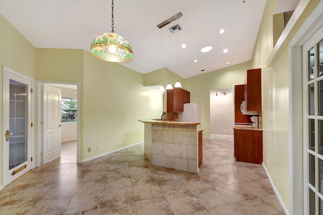 kitchen featuring sink, vaulted ceiling, kitchen peninsula, white fridge, and pendant lighting