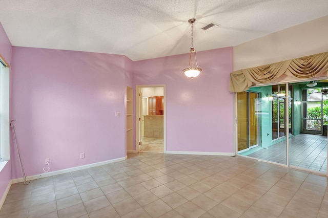 tiled empty room featuring vaulted ceiling and a textured ceiling