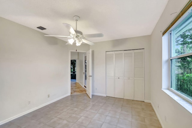 unfurnished bedroom with light tile patterned floors, ceiling fan, and a closet