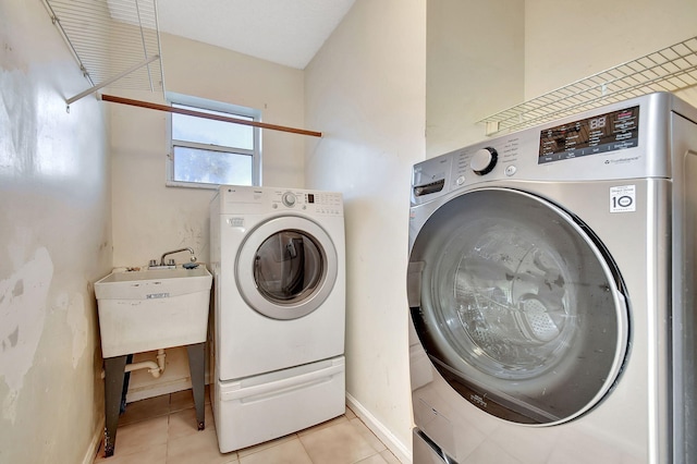 clothes washing area featuring sink, washer and clothes dryer, and light tile patterned flooring