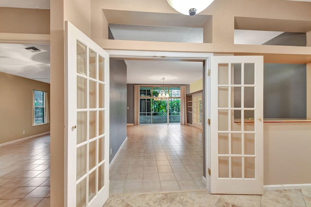 corridor featuring light tile patterned floors, an inviting chandelier, and french doors