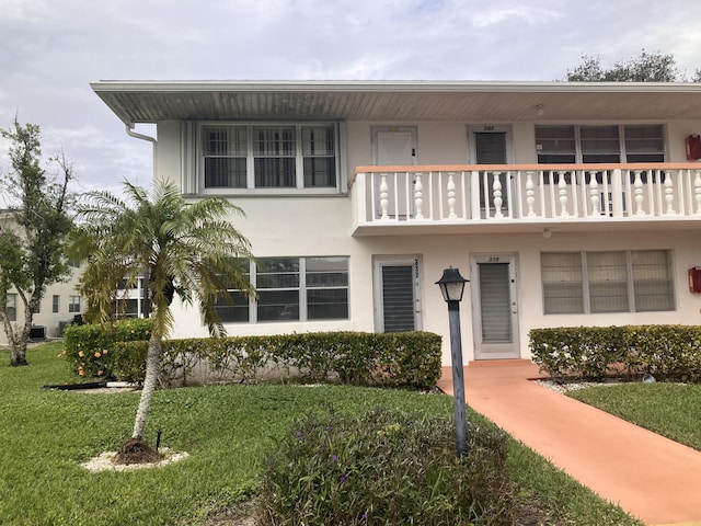 view of front of house with a front yard and a balcony