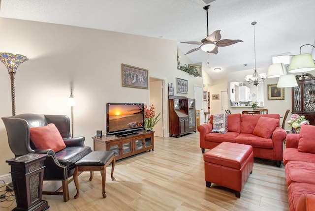 living room with lofted ceiling, ceiling fan with notable chandelier, and light hardwood / wood-style flooring