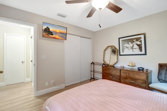 bedroom with ceiling fan, light hardwood / wood-style floors, a closet, and a textured ceiling