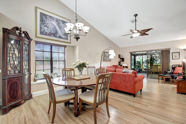 dining space featuring lofted ceiling, plenty of natural light, ceiling fan with notable chandelier, and light hardwood / wood-style flooring