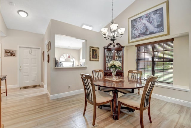 dining space with vaulted ceiling, a notable chandelier, and light wood-type flooring