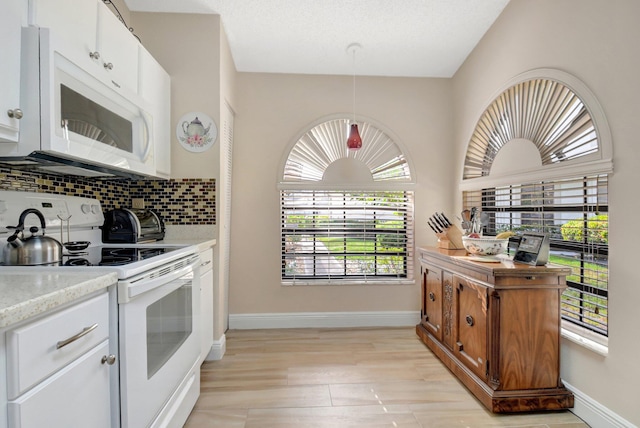 kitchen with light stone counters, light wood-type flooring, white appliances, decorative backsplash, and white cabinets