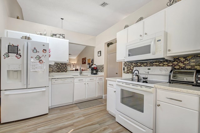 kitchen featuring tasteful backsplash, white appliances, and white cabinets