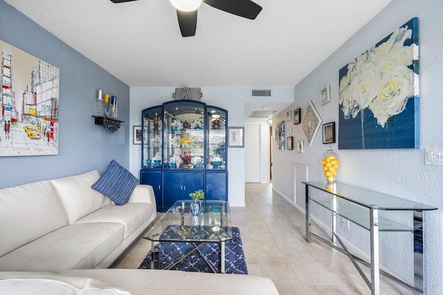 living room with tile patterned flooring, ceiling fan, and a textured ceiling