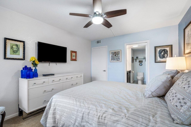 carpeted bedroom with ensuite bathroom and ceiling fan