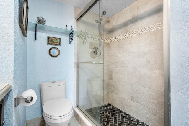 bathroom featuring toilet, a shower with shower door, and a textured ceiling