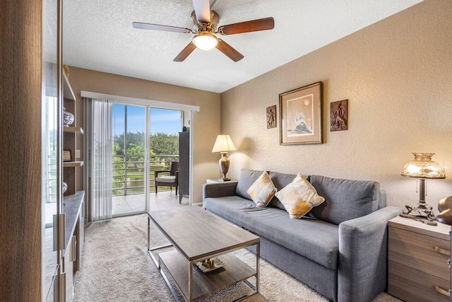 living room featuring ceiling fan, light colored carpet, and a textured ceiling