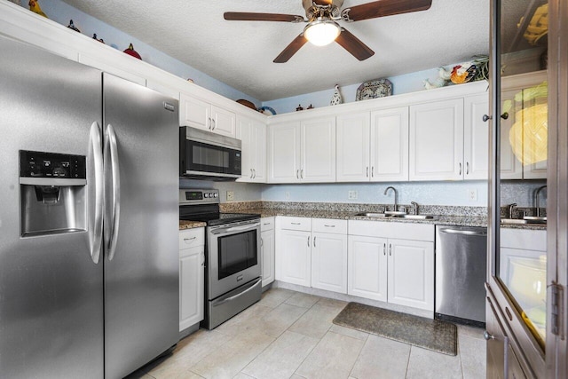 kitchen with white cabinetry, sink, dark stone countertops, stainless steel appliances, and a textured ceiling