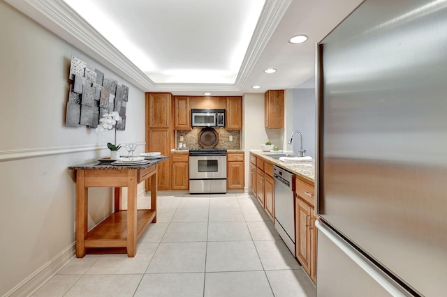 kitchen featuring appliances with stainless steel finishes, tasteful backsplash, sink, light tile patterned floors, and a tray ceiling