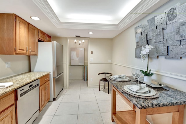 kitchen featuring stainless steel appliances, ornamental molding, dark stone counters, and a tray ceiling