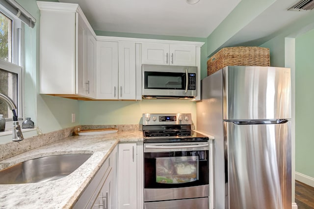 kitchen featuring light stone counters, sink, stainless steel appliances, and white cabinets