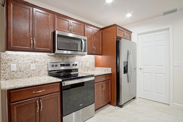 kitchen with light tile patterned floors, light stone counters, visible vents, appliances with stainless steel finishes, and decorative backsplash