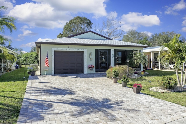 view of front facade featuring metal roof, a garage, decorative driveway, stucco siding, and a front lawn